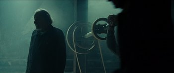 Movie still from “Taken 2” (2012), directed by Olivier Megaton – A person holding a steering wheel in front of a projector; Medium shot, Over the shoulder angle