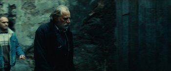 Movie still from “Taken 2” (2012), directed by Olivier Megaton – An old man with a beard is standing in the woods; Close Up shot, Low angle