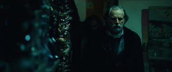 Movie still from “Taken 2” (2012), directed by Olivier Megaton – A man standing next to a stack of donuts; Medium shot, Low angle