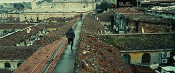 Movie still from “Taken 2” (2012), directed by Olivier Megaton – A man is walking down the side of the roof of a building; Extreme Wide shot, High angle