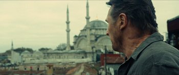 Movie still from “Taken 2” (2012), directed by Olivier Megaton – A man looking out over a city with a mosque in the background; Close Up shot, Low angle
