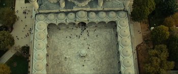 An aerial view of a building with a lot of people walking around it