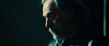 Movie still from “Taken 2” (2012), directed by Olivier Megaton – An old man with a beard is looking down at the ground; Close Up shot, Over the shoulder angle