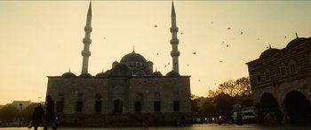 Movie still from “Taken 2” (2012), directed by Olivier Megaton – A large building with a bunch of birds flying around it; Extreme Wide shot, Low angle