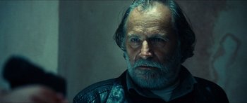 Movie still from “Taken 2” (2012), directed by Olivier Megaton – An old man with a beard and a leather jacket looking at the camera; Close Up shot, Low angle