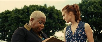 Two women are looking at a book together outside