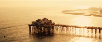 A pier with a house on top of it in the middle of the ocean