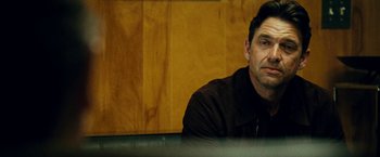 Movie still from “Taken 3” (2014), directed by Olivier Megaton – A person sitting in front of a wooden wall; Close Up shot, Over the shoulder angle