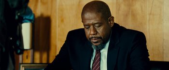 Movie still from “Taken 3” (2014), directed by Olivier Megaton – A man in a black suit and a red tie; Close Up shot, Over the shoulder angle