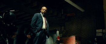 Movie still from “Taken 3” (2014), directed by Olivier Megaton – A man in a suit and tie standing next to a brick wall; Medium shot, Low angle