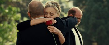 Movie still from “Taken 3” (2014), directed by Olivier Megaton – A man and a woman hug while holding a red rose; Close Up shot, Over the shoulder angle