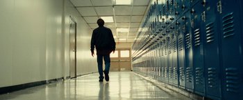 Movie still from “Taken 3” (2014), directed by Olivier Megaton – A man walking down a hallway in front of a row of school lockers; Wide shot, Low angle