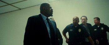 Movie still from “Taken 3” (2014), directed by Olivier Megaton – A man in a suit and tie standing next to a man in a police uniform; Medium shot, Over the shoulder angle