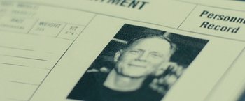 Movie still from “Taken 3” (2014), directed by Olivier Megaton – An old photo of a man's face on a document; Extreme Close Up shot, Overhead angle