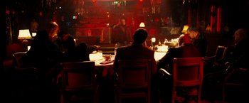 Movie still from “Taken 3” (2014), directed by Olivier Megaton – A group of people sitting at a table in front of a microphone; Wide shot, Over the shoulder angle