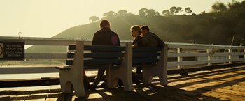 Movie still from “Taken 3” (2014), directed by Olivier Megaton – A group of people sitting on top of a wooden bench; Wide shot, Over the shoulder angle