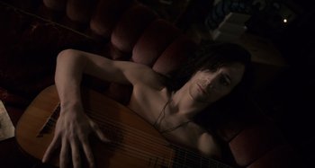 Movie still from “Only Lovers Left Alive” (2013), directed by Jim Jarmusch – A person laying on a couch with a guitar; Medium shot, High angle