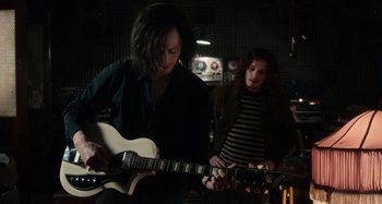 Movie still from “Only Lovers Left Alive” (2013), directed by Jim Jarmusch – A man playing an electric guitar while another man watches; Medium shot, Over the shoulder angle