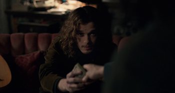 Movie still from “Only Lovers Left Alive” (2013), directed by Jim Jarmusch – A man sitting down holding a piece of paper in his hand; Medium shot, Over the shoulder angle