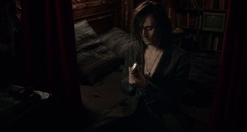 Movie still from “Only Lovers Left Alive” (2013), directed by Jim Jarmusch – A man sitting on a bed looking at a cell phone; Medium shot, High angle
