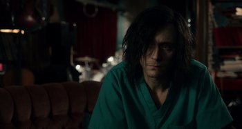 Movie still from “Only Lovers Left Alive” (2013), directed by Jim Jarmusch – A man with long black hair sitting on a couch; Medium shot, Over the shoulder angle