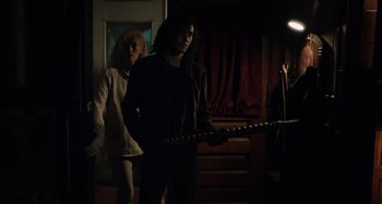 Movie still from “Only Lovers Left Alive” (2013), directed by Jim Jarmusch – Two people in a dark room holding a wooden stick; Medium shot, Low angle
