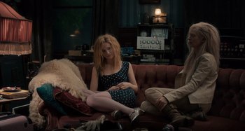 Movie still from “Only Lovers Left Alive” (2013), directed by Jim Jarmusch – A woman sitting on top of a red couch next to two other people; Medium shot, High angle