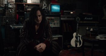 Movie still from “Only Lovers Left Alive” (2013), directed by Jim Jarmusch – A man sitting in a room next to an electric guitar; Medium shot, Over the shoulder angle