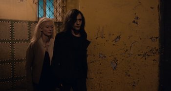 Movie still from “Only Lovers Left Alive” (2013), directed by Jim Jarmusch – A man and a woman standing next to each other in front of a wall; Medium shot, Low angle