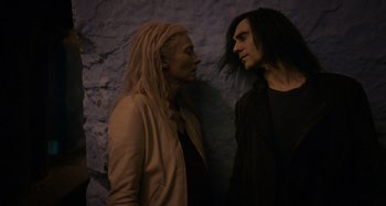 Movie still from “Only Lovers Left Alive” (2013), directed by Jim Jarmusch – A man and a woman standing next to each other in front of a stone wall; Medium shot, Low angle
