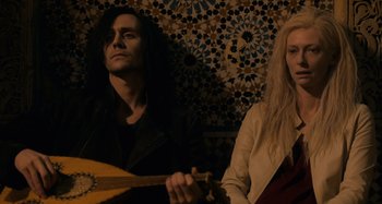 Movie still from “Only Lovers Left Alive” (2013), directed by Jim Jarmusch – A man and a woman sitting next to each other holding a guitar; Medium shot, Low angle