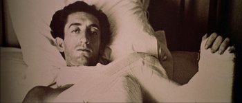 Movie still from “Talk to Her” (2002), directed by Pedro Almodóvar – A man laying in a bed under a white blanket; Close Up shot, High angle