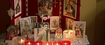 Movie still from “Talk to Her” (2002), directed by Pedro Almodóvar – A table topped with candles and pictures on it; Medium shot, High angle