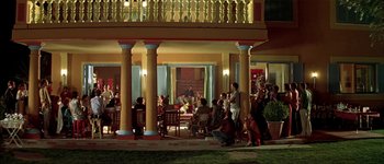 Movie still from “Talk to Her” (2002), directed by Pedro Almodóvar – A group of people sitting outside of a building at night; Extreme Wide shot, High angle