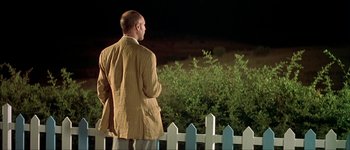 Movie still from “Talk to Her” (2002), directed by Pedro Almodóvar – A man standing in front of a white picket fence at night; Medium shot, Over the shoulder angle