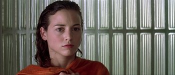 Movie still from “Talk to Her” (2002), directed by Pedro Almodóvar – A young woman in an orange shirt looking at the camera; Close Up shot, Over the shoulder angle