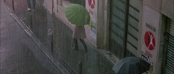 Movie still from “Talk to Her” (2002), directed by Pedro Almodóvar – A person with an umbrella walking in the rain; Extreme Wide shot, Overhead angle