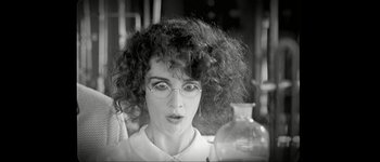 Movie still from “Talk to Her” (2002), directed by Pedro Almodóvar – A black and white photo of a woman with curly hair and glasses; Close Up shot, Over the shoulder angle