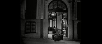 Movie still from “Talk to Her” (2002), directed by Pedro Almodóvar – A man pulling a suit case down a sidewalk; Wide shot, High angle