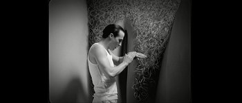 Movie still from “Talk to Her” (2002), directed by Pedro Almodóvar – A black and white photo of a man in a tank top; Medium shot, Low angle