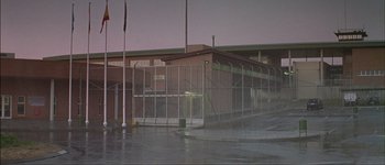 Movie still from “Talk to Her” (2002), directed by Pedro Almodóvar – A building that has a fence around it; Extreme Wide shot, High angle