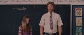 Movie still from “Talladega Nights: The Ballad of Ricky Bobby” (2006), directed by Adam McKay – A man standing next to a girl in front of a blackboard; Medium shot, Over the shoulder angle