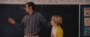 Movie still from “Talladega Nights: The Ballad of Ricky Bobby” (2006), directed by Adam McKay – A man and a boy standing next to each other in a room; Medium shot, Over the shoulder angle