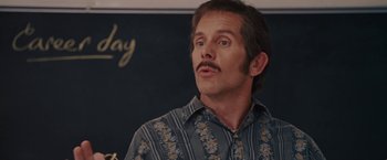Movie still from “Talladega Nights: The Ballad of Ricky Bobby” (2006), directed by Adam McKay – A man with a mustache wearing a blue and white striped shirt; Close Up shot, Low angle