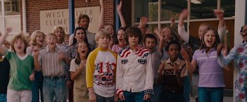 Movie still from “Talladega Nights: The Ballad of Ricky Bobby” (2006), directed by Adam McKay – A group of children standing next to each other in front of a building; Medium shot, Low angle