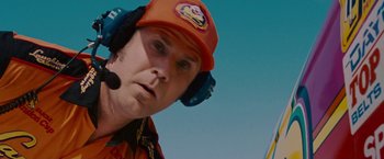 Movie still from “Talladega Nights: The Ballad of Ricky Bobby” (2006), directed by Adam McKay – A man wearing a red hat and ear muffs; Close Up shot, Over the shoulder angle
