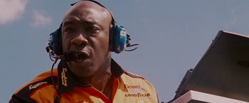 Movie still from “Talladega Nights: The Ballad of Ricky Bobby” (2006), directed by Adam McKay – A man with a yellow shirt and blue ear muffs; Close Up shot, Low angle