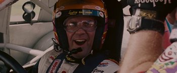 Movie still from “Talladega Nights: The Ballad of Ricky Bobby” (2006), directed by Adam McKay – A man in a racing suit and a helmet; Close Up shot, Low angle
