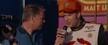 Movie still from “Talladega Nights: The Ballad of Ricky Bobby” (2006), directed by Adam McKay – A man is being interviewed by an announcer; Close Up shot, Over the shoulder angle