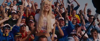 Movie still from “Talladega Nights: The Ballad of Ricky Bobby” (2006), directed by Adam McKay – A woman is smiling in the stands of a race; Medium shot, Low angle